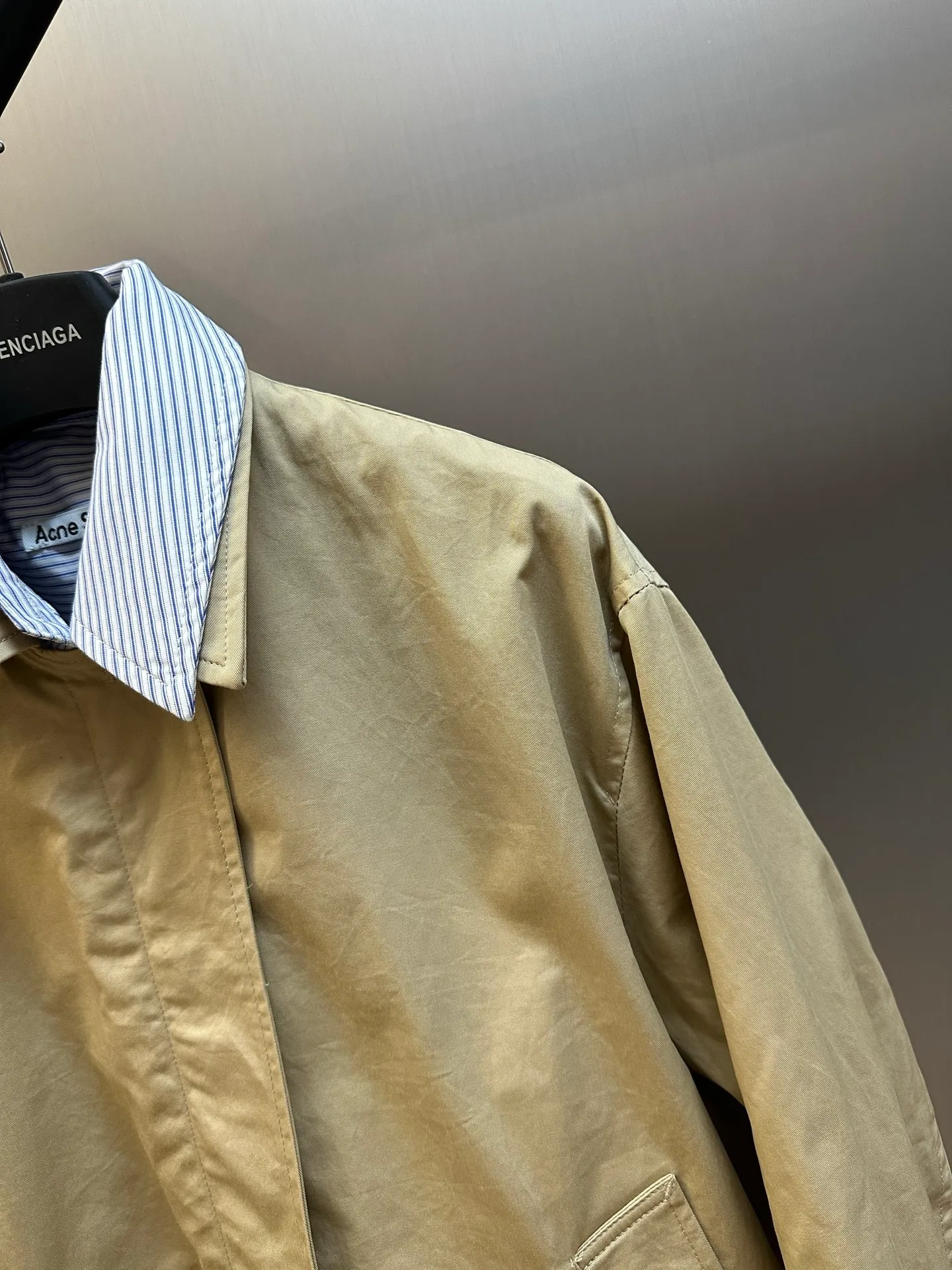 Ac Hot Sale genuine two-piece jacket. The main body is made of high-density twill cotton poplin. It has been processed by pre-shrunk washing process. The cloth surface is smooth and clean, with a matte and soft workwear texture. The stiffness is just right. The short version can be held up three-dimensionally and is not easy to collapse and wrinkle. It is suitable for daily commuting and outdoor use. The inner shirt is made of yarn-dyed blue and white striped cotton. The yarn-dyed stripes have clear texture and will not turn white or smudged after washing. The fabric surface is breathable and dry, and the collar and cuffs are folded and exposed to form contrasting color layers. The difficulty of the whole piece lies in the combined sewing of two fake pieces. The shirt collar and jacket collar are double-stitched and seamed. The collar corners are shaped and hemmed, and the folding shape is neat and will not collapse and curl. The placket adopts a double-layer structure of zipper + hidden buckle windproof fabric. The inner and outer layers of fabric are aligned and sewn together, and the wiring is even and fine. There are adjustable tabs on both sides of the hem, which can be freely tightened to suit different styles. The back printing adopts embossed relief technology, which blends into the fabric and is low-key and unobtrusive. The zipper is made of nylon zipper with metal teeth. The teeth are polished smoothly and will not get stuck after repeated pulling. The zipper headband has brand engraved details. The buttons are divided into two systems: the outer part is made of horn dark brown resin buttons with natural texture and high-end matte texture; the inner shirt is equipped with Cream White pearlescent four-eye buttons, echoing the blue and white striped fabric. size：xs s m l